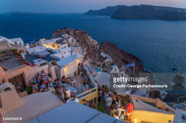 tourists watching the sunset in oia, santorini, greece - oia santorini stockfoto's en -beelden