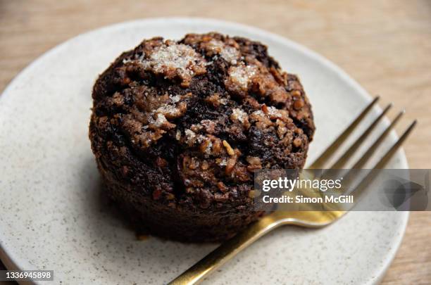 chocolate and zucchini muffin on a plate on a wooden cafe table - muffin stockfoto's en -beelden