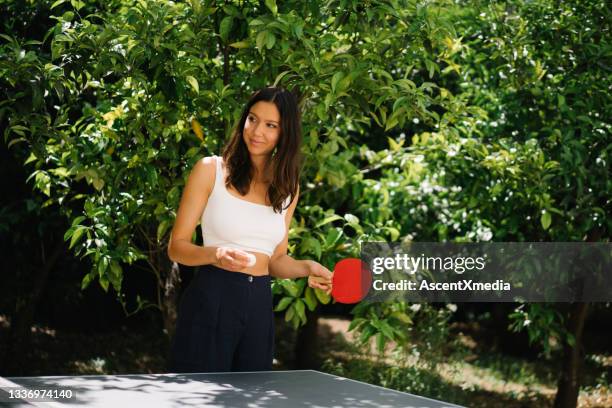young woman prepares to play table tennis outdoors - women's table tennis stockfoto's en -beelden