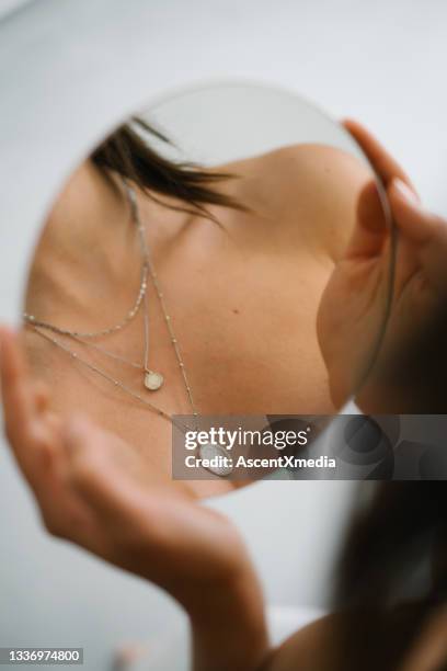 young woman looks at necklaces in mirror - necklace stock pictures, royalty-free photos & images