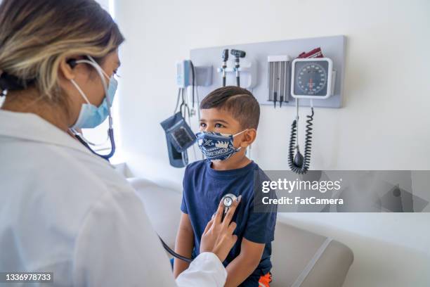 young boy wearing a mask at a doctor's office - pediatrician covid stock pictures, royalty-free photos & images