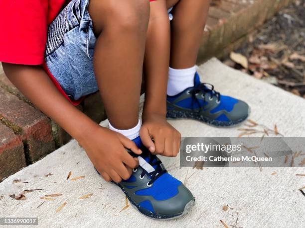 young african-american boy sits on front step at home to tie his shoe laces - boy tying shoes stock pictures, royalty-free photos & images