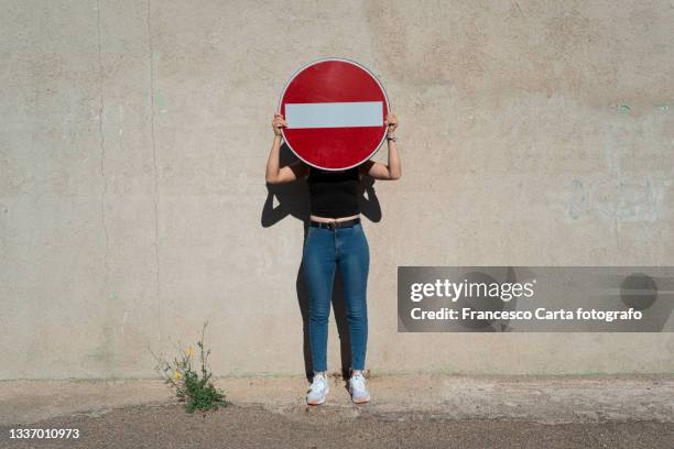 woman covering her face with a no entry sign - verboden stockfoto's en -beelden