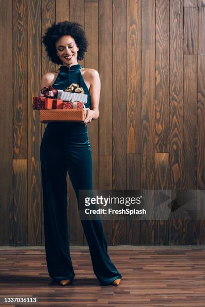 bella donna afroamericana che tiene regali di natale (sfondo marrone) - blue jumpsuit foto e immagini stock