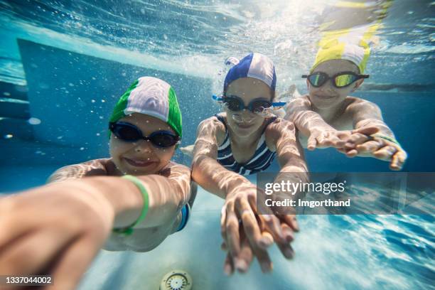 three happy kids swimming underwater in pool - swimming cap stock pictures, royalty-free photos & images