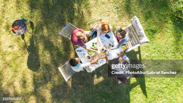 happy young friends toasting beer bottles in garden - friends toasting above table stock-fotos und bilder