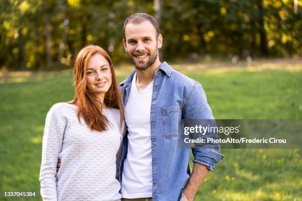 portrait of smiling young couple enjoying a stroll in a park - side by side stock pictures, royalty-free photos & images