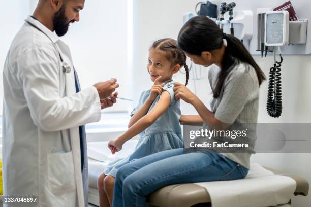 kleines mädchen in einer arztpraxis für eine impfinjektion - doctor visit stock-fotos und bilder