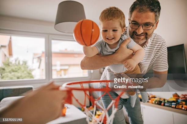 father and son having fun, playing basketball at home - toy basketball hoop stock pictures, royalty-free photos & images