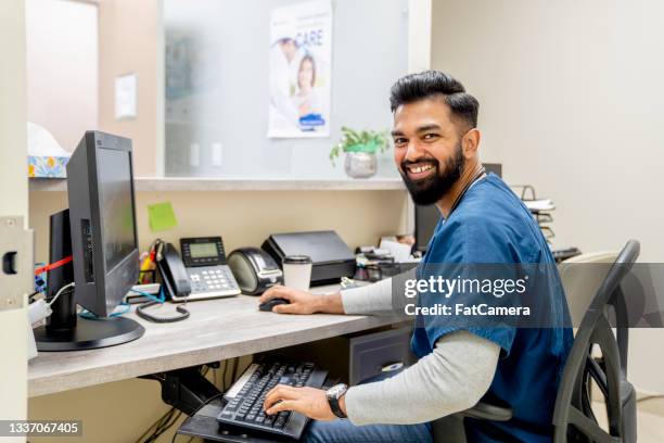 friendly male nurse receptionist at a medical clinic - reception stock pictures, royalty-free photos & images