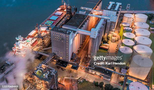 an aerial view of  oil storage tanks and an oil tanker at a power station - stock photo - raffinerie stock-fotos und bilder