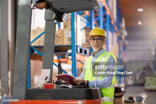 asian chinese senior warehouse worker operating forklift working in industry factory - operational technology stock pictures, royalty-free photos & images