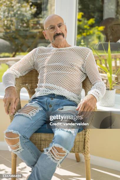 homem gay sênior relaxando em seu conservatório - camiseta de rede - fotografias e filmes do acervo