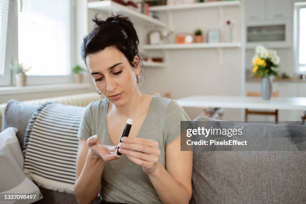 mujer que revisa el nivel de azúcar en la sangre - hipoglicemia fotografías e imágenes de stock