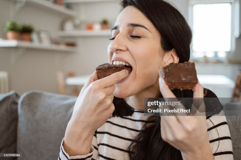 Frau isst ein Stück süßen Kuchen zu Hause