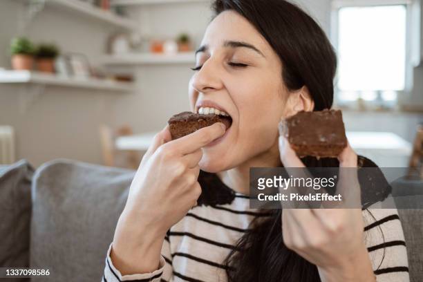 woman eating slice of sweet cake at home - eating cake stockfoto's en -beelden