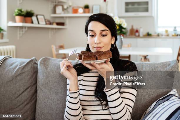 frau isst ein stück süßen kuchen zu hause - ertappt stock-fotos und bilder