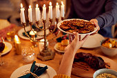 Close-up of Jewish couple passing food at dining table on Hanukkah.