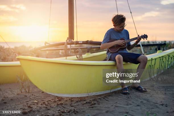 teenage boy playing ukulele on the beach - ukelele stock pictures, royalty-free photos & images