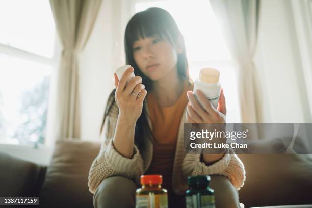asian woman choosing between supplements - prescription label stock pictures, royalty-free photos & images