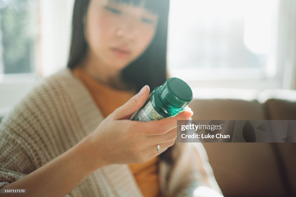 Asiatische Frau, die zwischen Nahrungsergänzungsmitteln wählt