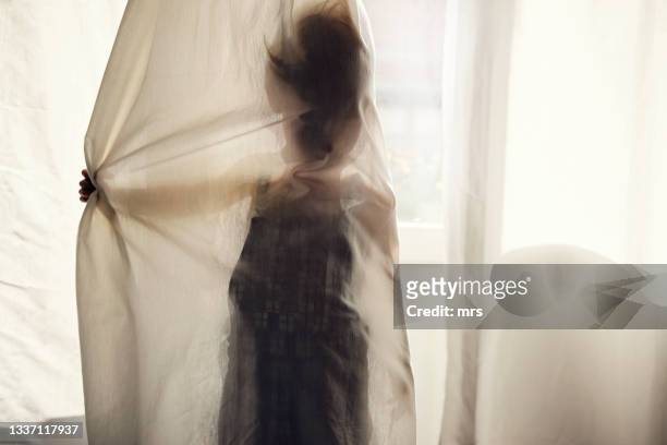 little boy hiding behind curtain - hide stockfoto's en -beelden