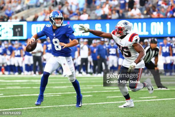 Daniel Jones of the New York Giants is pursued by Josh Uche of the New England Patriots at MetLife Stadium on August 29, 2021 in East Rutherford, New...