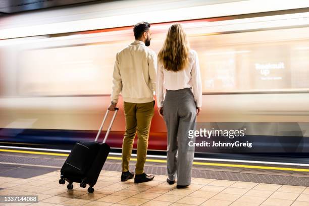 business partners waiting for their train on underground platform - man woman train station stockfoto's en -beelden