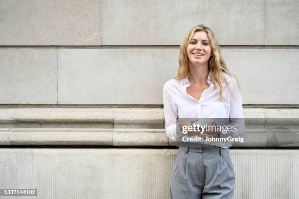 relaxed businesswoman taking a break with smart phone - businesswoman standing facing forward bildbanksfoton och bilder