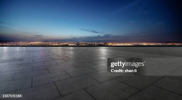 empty ground against urban skyline at night - sol en ciment photos et images de collection