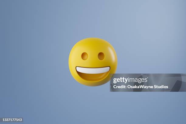 computer graphics of yellow smiling round emoji isolated on pastel blue background - anthropomorphic face stockfoto's en -beelden