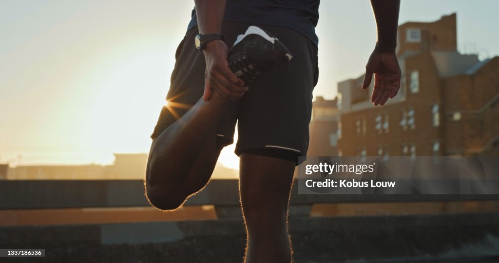 Closeup shot of an unrecognisable man stretching his legs while exercising outdoors