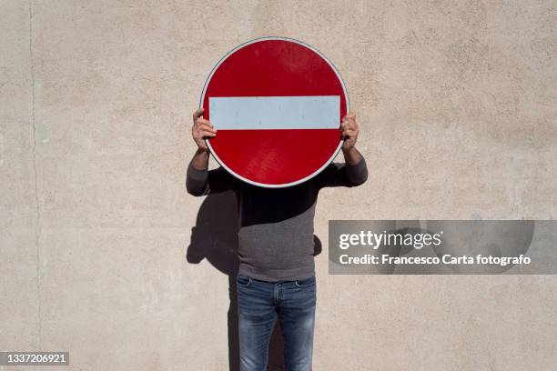 man covering her face with a no entry sign - separation wall stock pictures, royalty-free photos & images