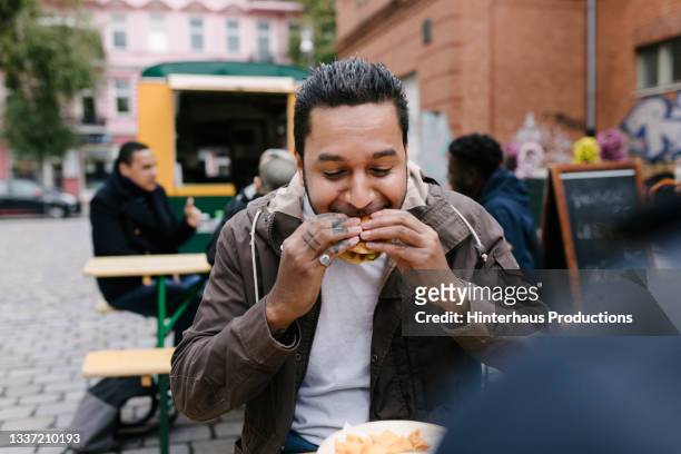 man eating burger from food truck - eating fast food stock-fotos und bilder
