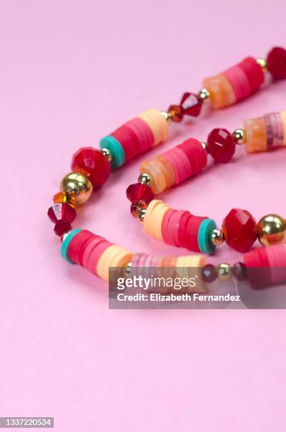 close-up of beaded jewelry on pink background. copy space on image. - beads stock pictures, royalty-free photos & images