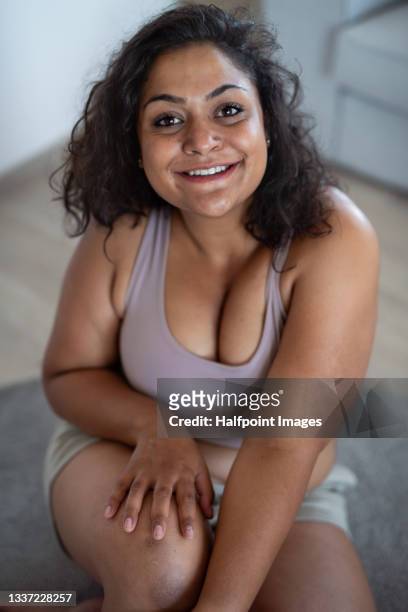 portrait of beautiful young overweight woman indoors at home, looking at camera. - heavy set women stock pictures, royalty-free photos & images