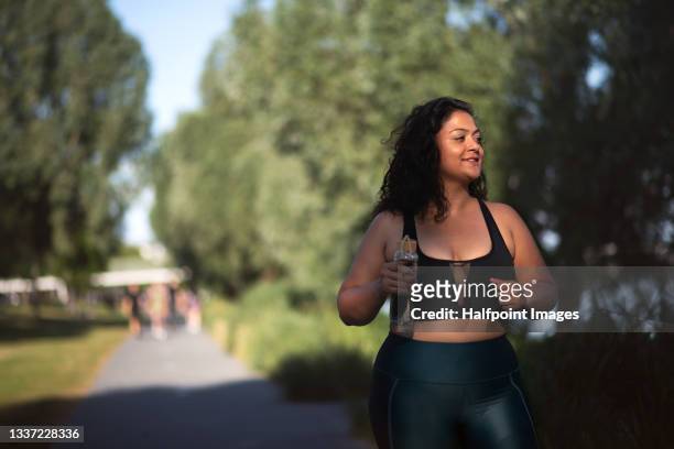 portrait of beautiful young overweight woman running outdoors in city,  doing exercise. - fat asian woman stock-fotos und bilder