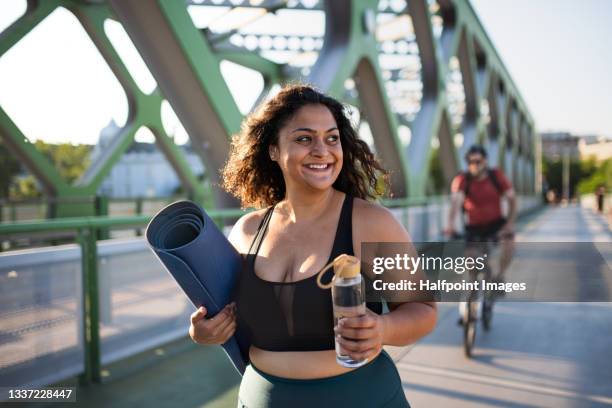 portrait of beautiful young overweight woman walking outdoors on bridge in city,  exercise concept. - träningsmatta bildbanksfoton och bilder