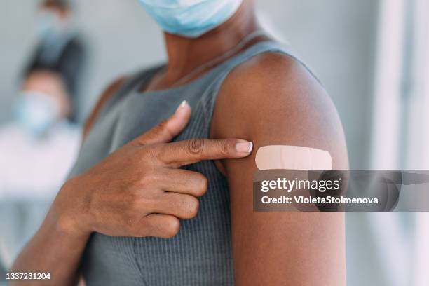 businesswoman showing her arm after getting vaccinated in the office. - plaster construction material stock pictures, royalty-free photos & images