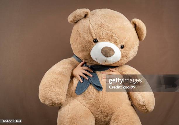 child holding a big teddy bear to block himself on brown background - big hug stock pictures, royalty-free photos & images