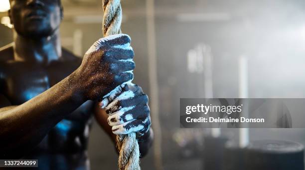 cropped shot of an unrecognizable young man exercising on climbing ropes at the gym - hard talk stockfoto's en -beelden