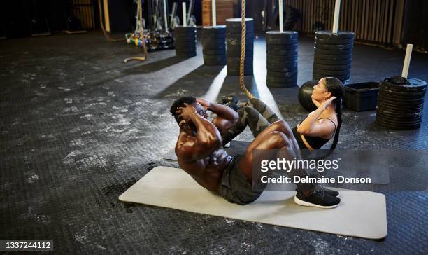 aufnahme von zwei jungen gym-kumpels, die sich im fitnessstudio auf dem boden aufsetzen - black female bodybuilder stock-fotos und bilder