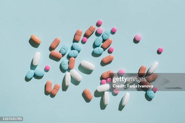 colorful pills and capsules on blue background. minimal medical concept. flat lay, top view. - tablette stock-fotos und bilder