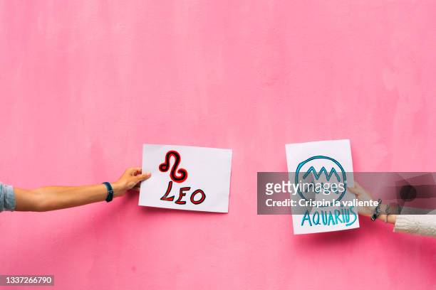 woman's arms holding signs with leo and aquariums, zodiac signs. - dinge die zusammenpassen stock-fotos und bilder