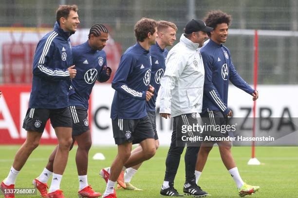 Hans-Dieter Flick, Head Coach of Germany talks to his player Leroy Sane during a training session at ADM-Sportpark on August 30, 2021 in Stuttgart,...