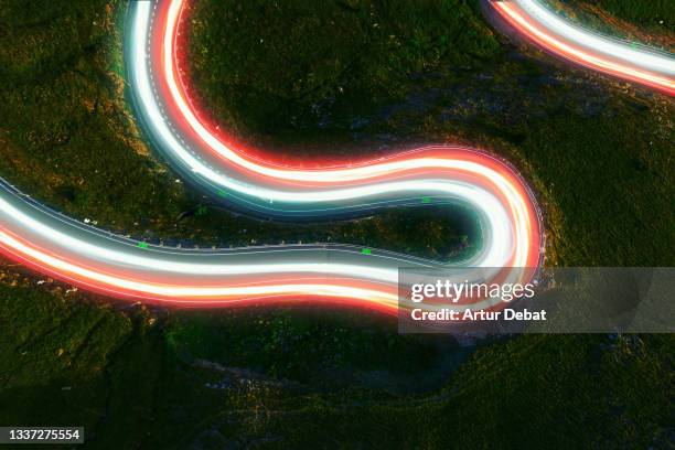 directly above view by drone of stunning colorful light trails in curvy road. - elektrofahrzeug stock-fotos und bilder