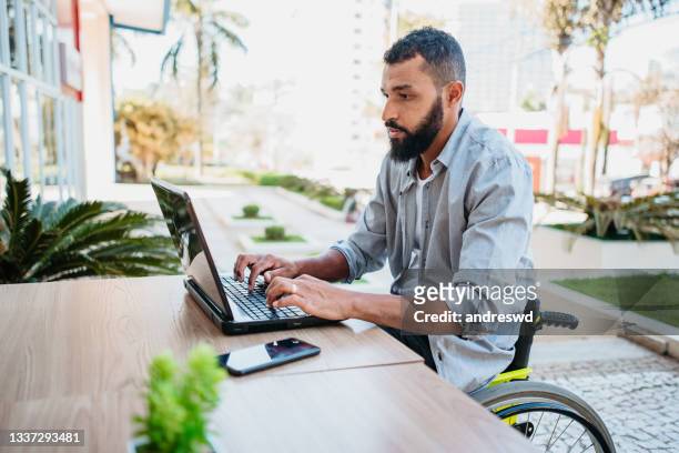 rollstuhlfahrer, der in der cafeteria am computer arbeitet - arbeiten outdoor stadt laptop stock-fotos und bilder