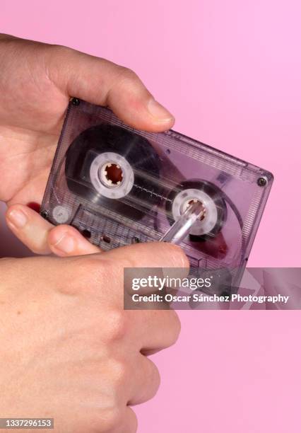 hand rewinding a cassette tape with a pen on pink background - pop music imagens e fotografias de stock