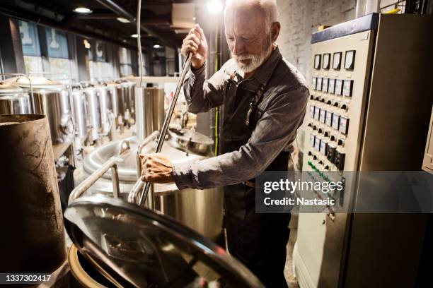 senior worker loading the hops crop into a tank - fotoshop stockfoto's en -beelden