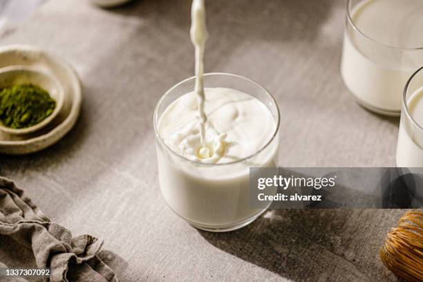 frische milch in glas gießen - dairy product stock-fotos und bilder